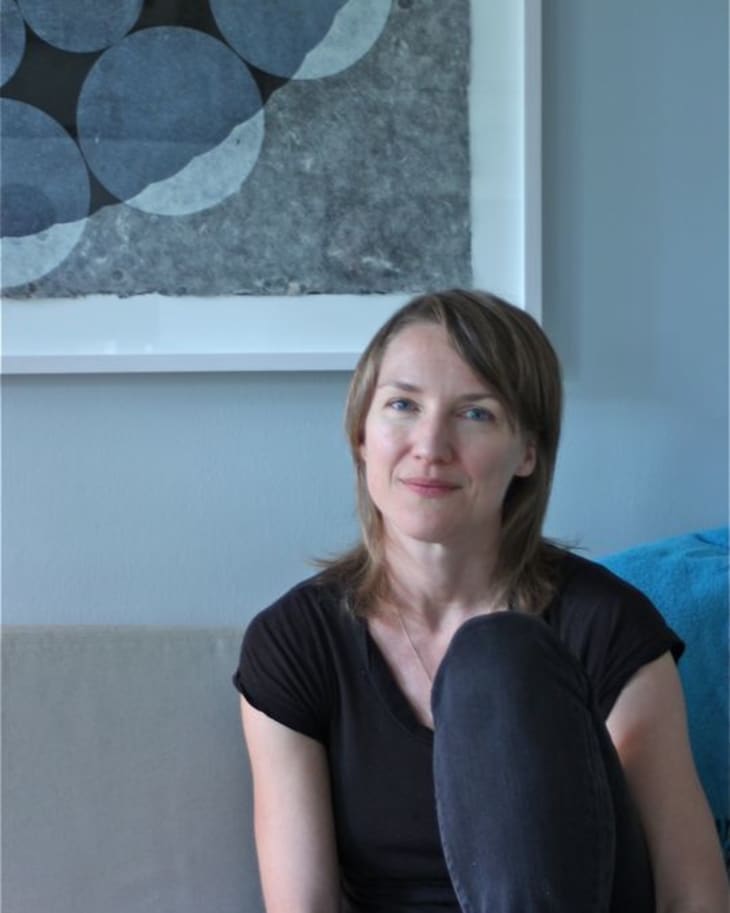 Woman sitting on a sofa with abstract circular artwork in the background.