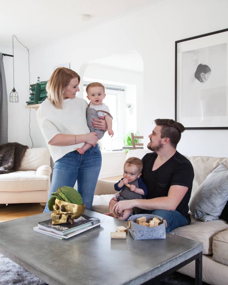 Family in living room with a concrete coffee table, gold skull decor, and framed portrait on the wall.