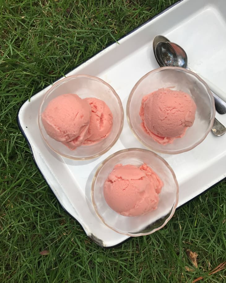 Watermelon sherbet in small ice cream cups, set on a tray with three teaspoons