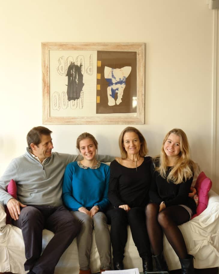Family of four sitting on a white sofa, with abstract art on the wall behind them.