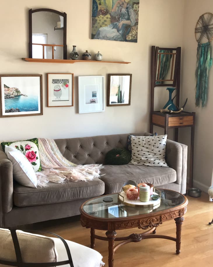 Cozy living room with a tufted sofa, decorative pillows, framed art, and a wooden coffee table with candles.