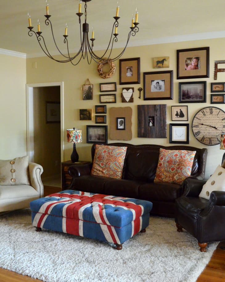 Living room with a leather sofa, Union Jack ottoman, gallery wall, and chandelier.