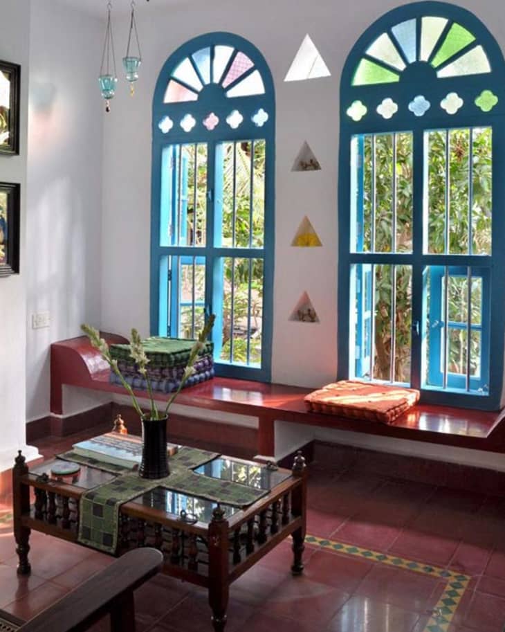 Cozy room with blue arched windows, colorful cushions, and a wooden coffee table with a vase.
