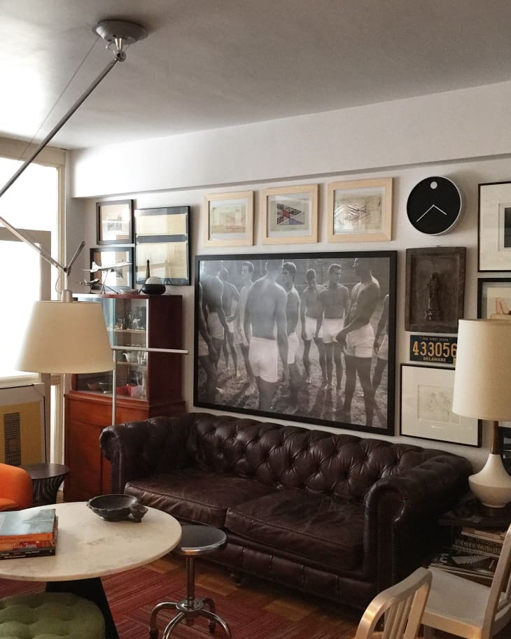 Living room with brown leather sofa, eclectic wall art, orange chair, and modern floor lamp.