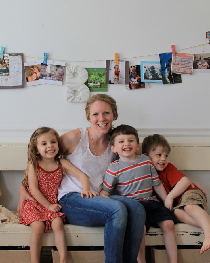 Woman sitting on a bench with three smiling children, photos clipped on a string behind them.