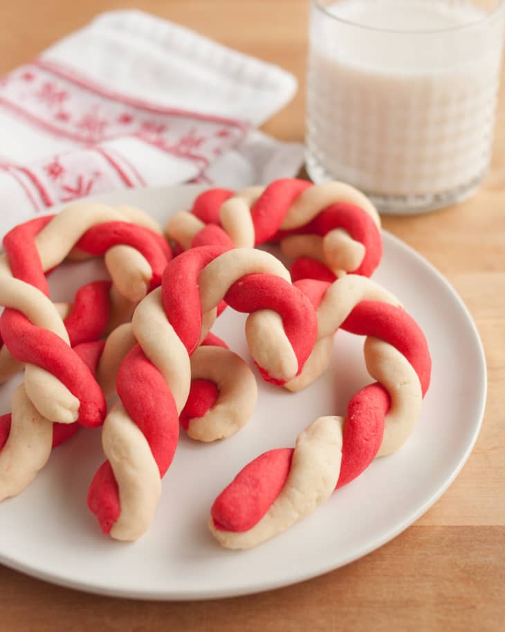 Candy cane cookies on a plate with a glass of milk in the background.