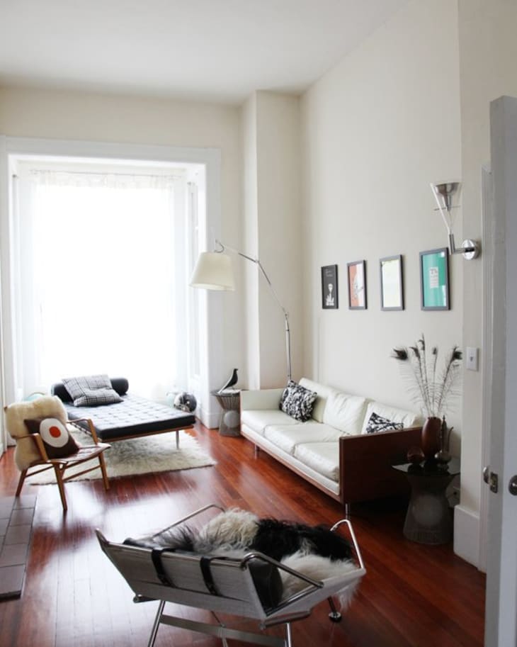 Modern living room with white sofa, framed art, floor lamp, and wooden floors.