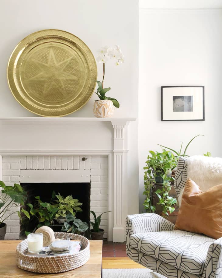A white brick fireplace with a large gold plate on the mantel