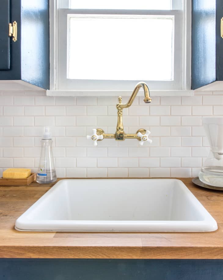 White kitchen sink with butcher block counter and white tile backsplash