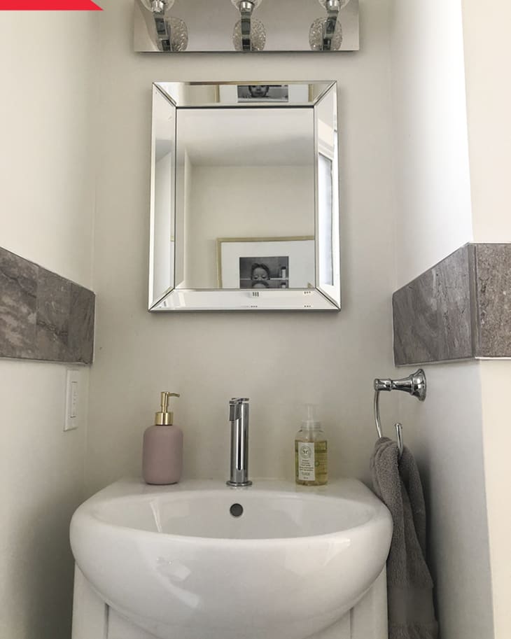 Small bathroom sink with a mirror, soap dispenser, and hand towel.