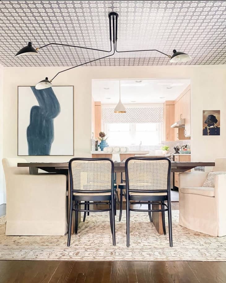 Neutral dining table and chairs with abstract blue artwork behind