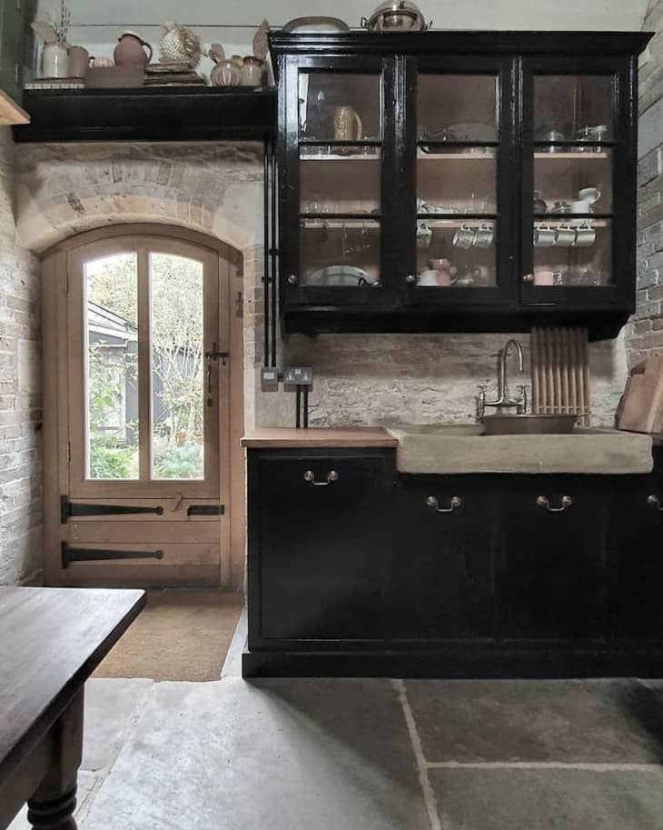 Kitchen with black cabinetry and brick walls