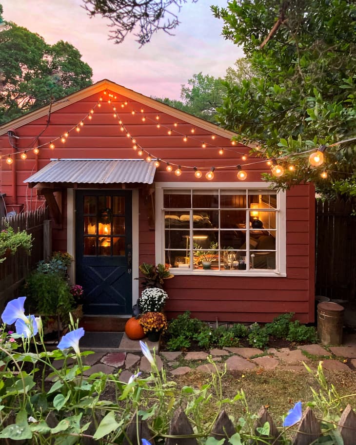 Small red accessory dwelling unit with blue flowers and white lights