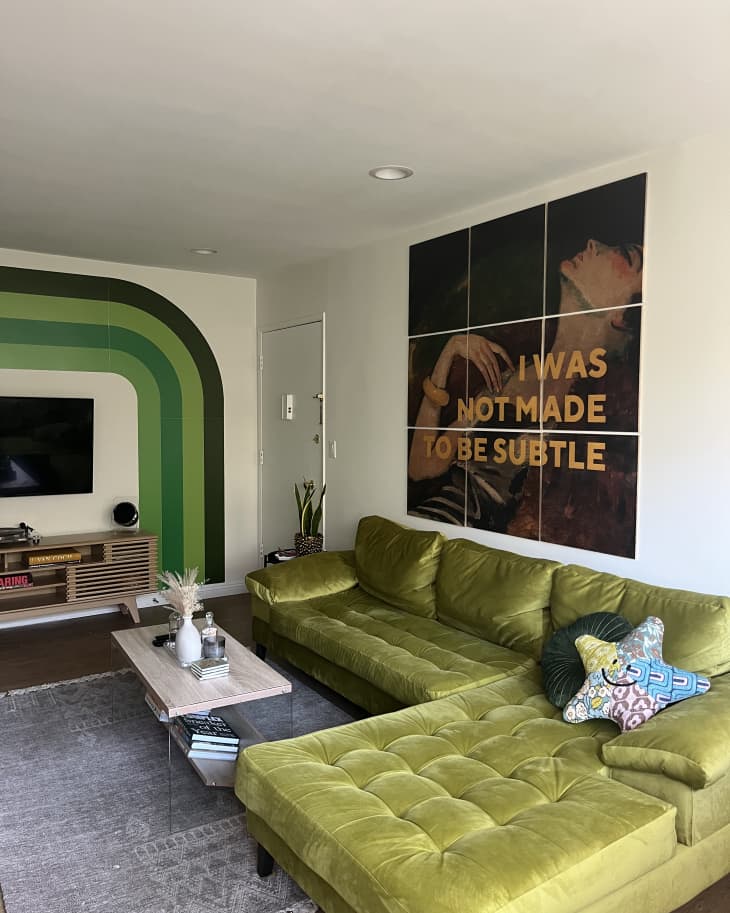 Sectional green and yellow couch by art on the wall