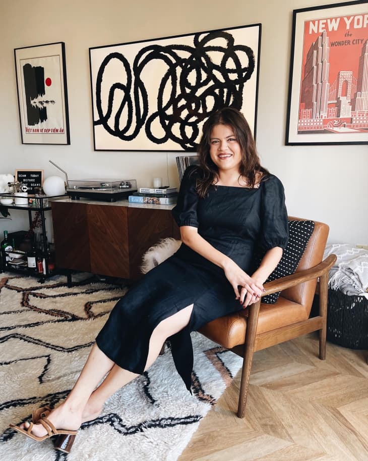 A woman sitting in a chair with large framed art behind her