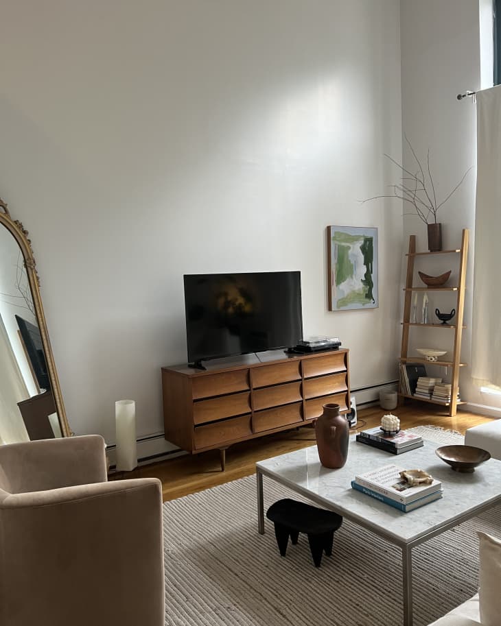 A living room with a wooden tv stand and a square coffee table