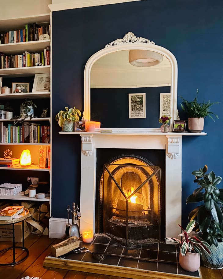 living room with fireplace, navy blue accent wall, white decorative trim, bookshelves