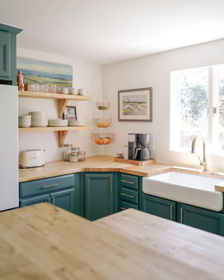 Ocean colored cabinets with gold hardware and butcher block countertops.