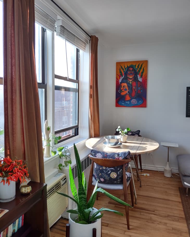 Small dining table beside sunny window in studio apartment.