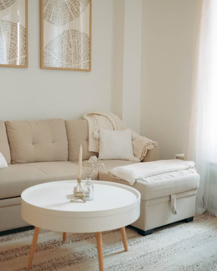 A tan couch next to a white round coffee table