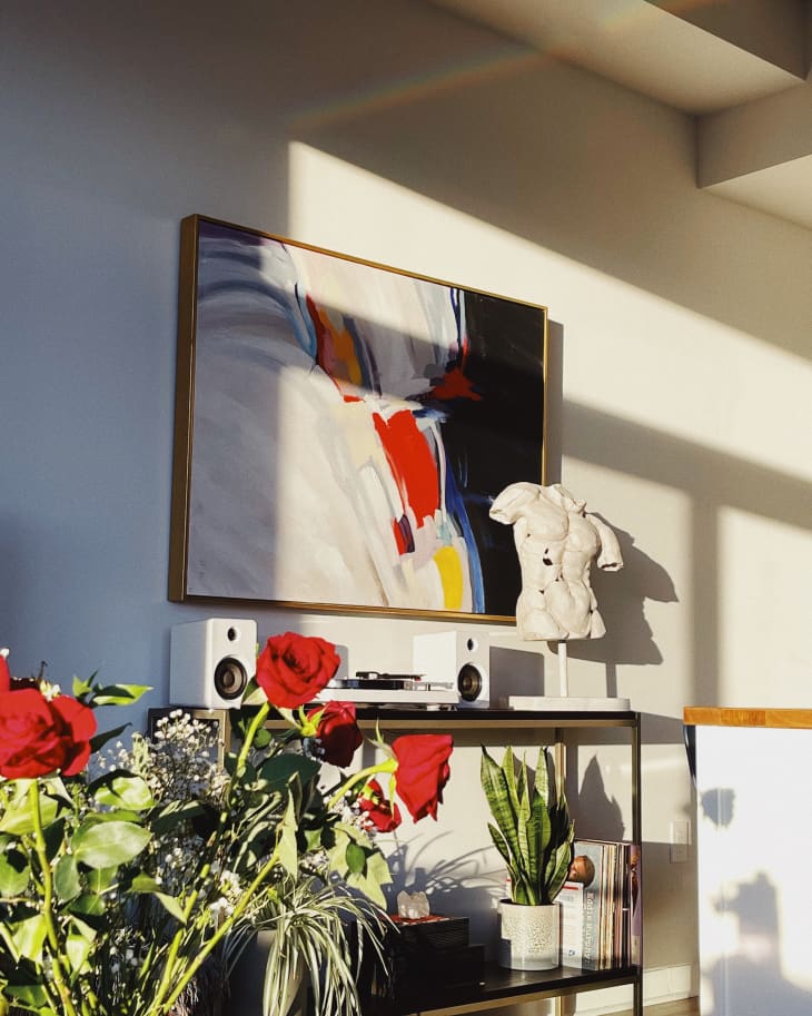 A painting above a table holding a sculpture