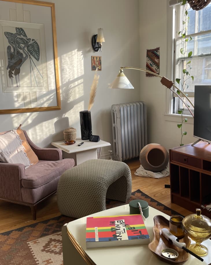 A cozy pink chair below a painting face the tv