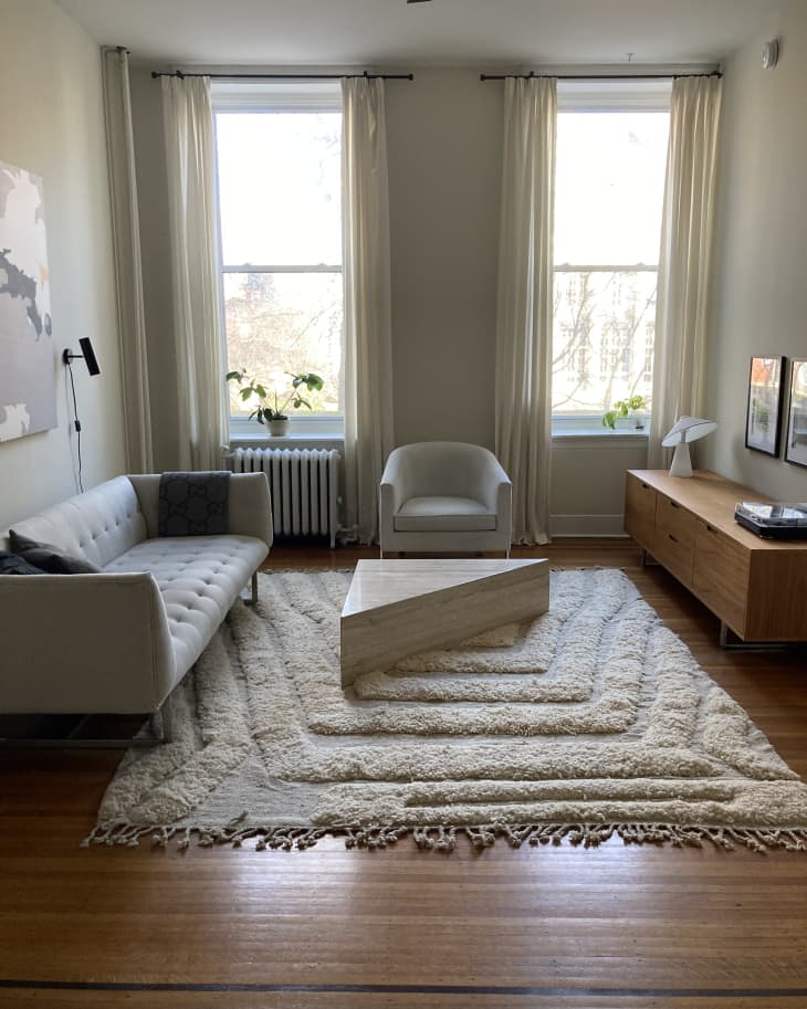 A large living room with two windows, a sofa, and a large rug