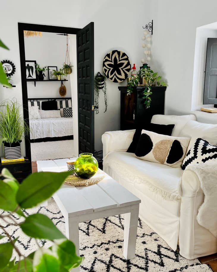 Black and white shag rug on floor in living room with white sofa topped with neutral colors decorative pillows.