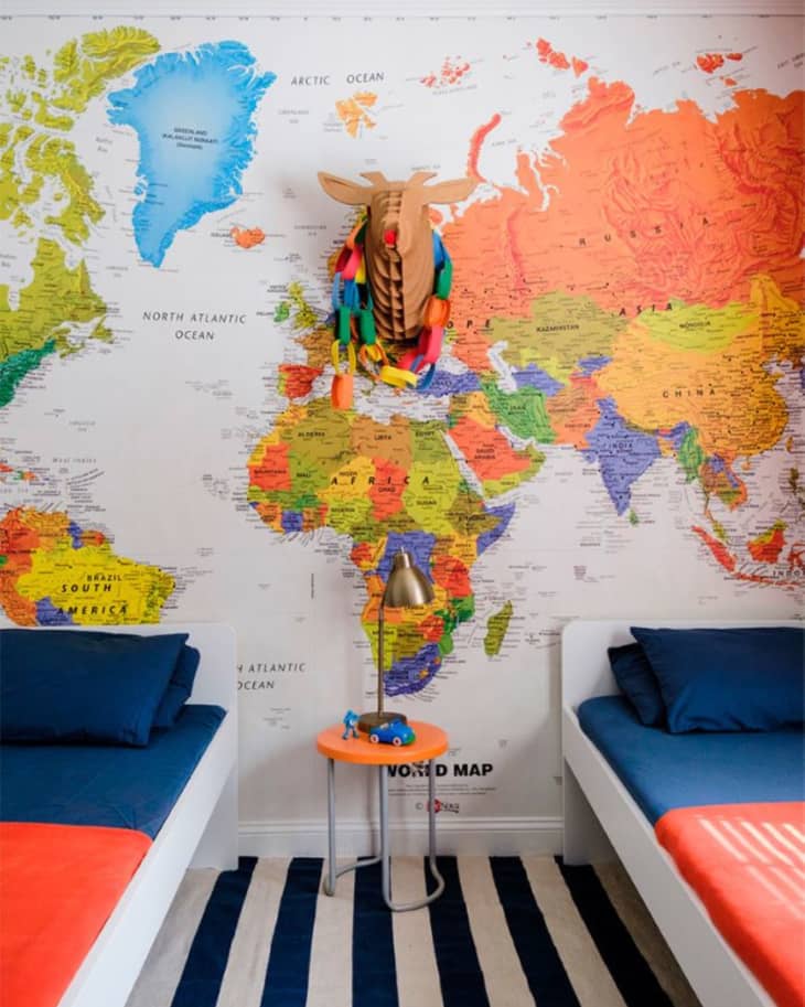 colorful map wall, black and white striped carpet, double beds, 3D deer head, clown nose