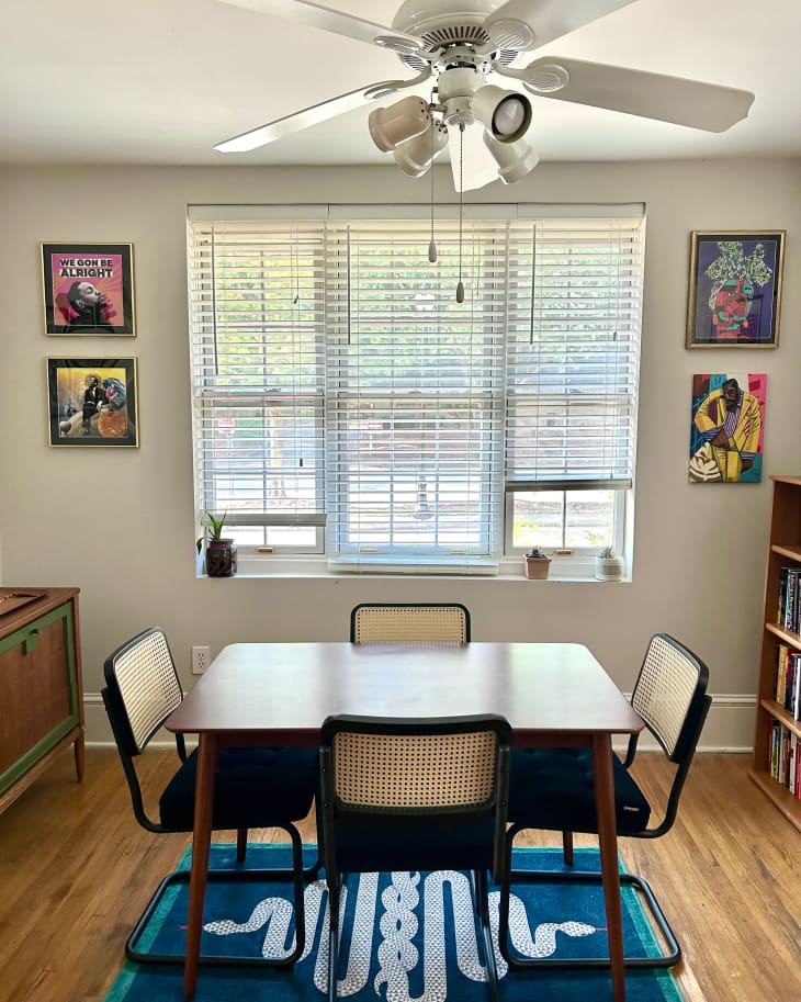 Cantilever dining chairs surround wooden square dining table in light filled dining room.