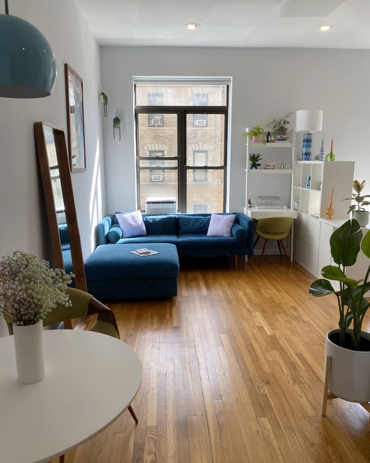 Sunny white NYC apartment with blue and other color accents, wood floor