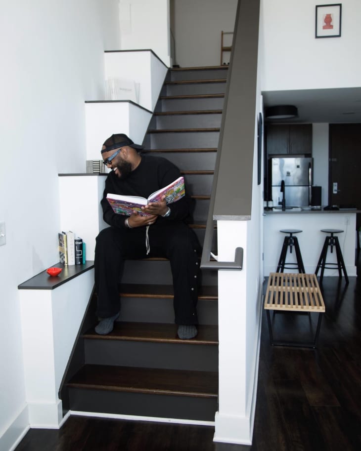 A man holding a book laughing on a black staircase
