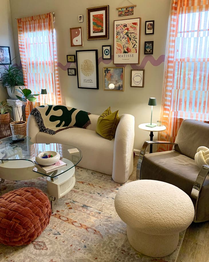 Eclectic apartment living room with boucle love seat and ottoman. Wavy decal runs through gallery wall.