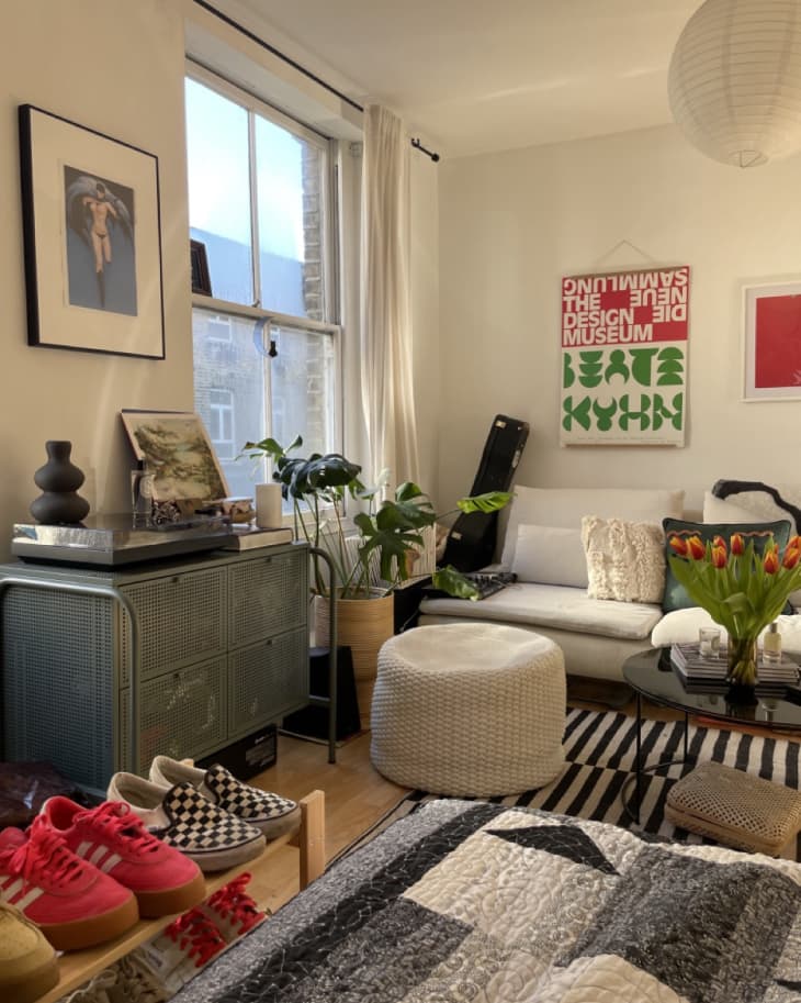 white living area of studio apartment with black and white striped rug and off white sofa
