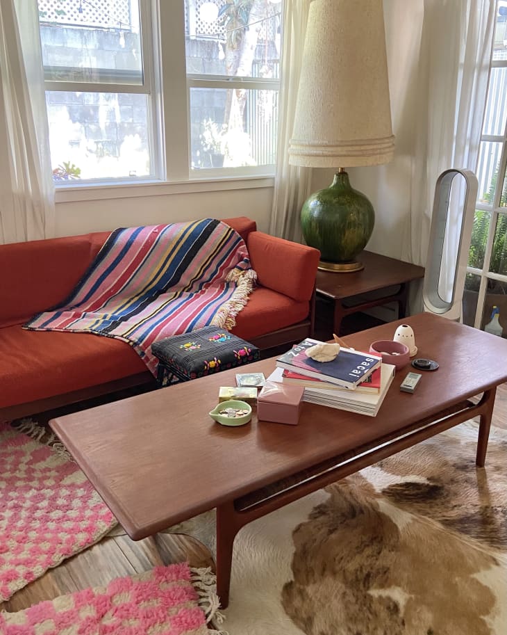 white living room with red sofa and layered rugs on floor