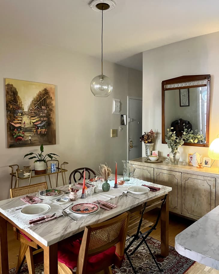 Glass pedant hangs over marble dining table.