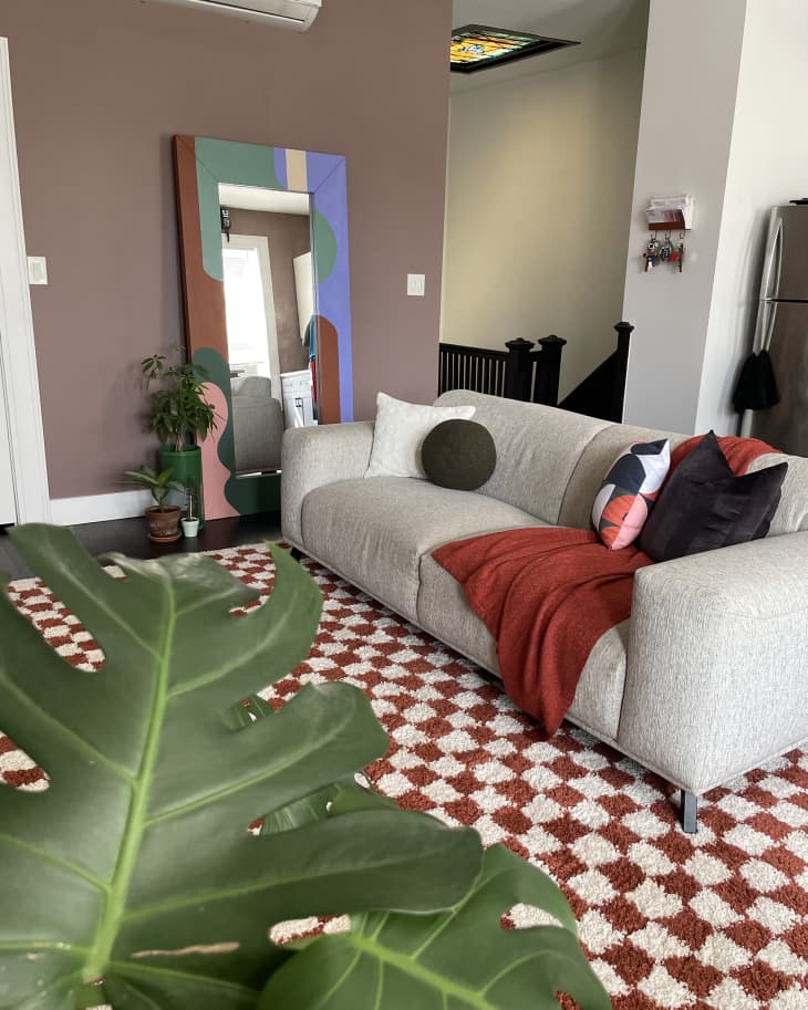 Living room with pale gray textured sofa, checked shag rug, and deep mauve/brown accent wall