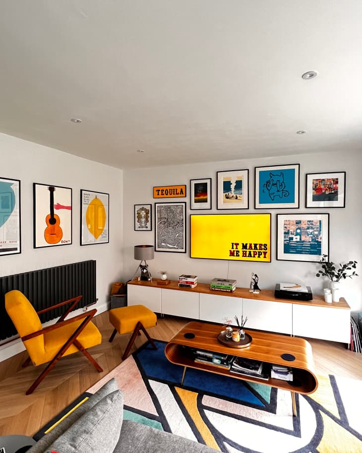 A wood-floored living room with gallery walls and a yellow lounge chair
