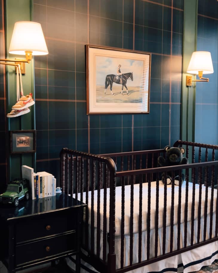 Green tartan wall covering flanked by sconces  behind crib in baby nursery