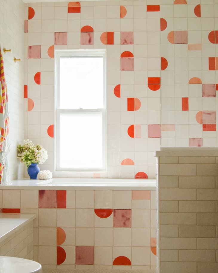 Kids bathroom with pink walls and gold fixtures, cream tile, white quartz countertops red and orange handmade tile