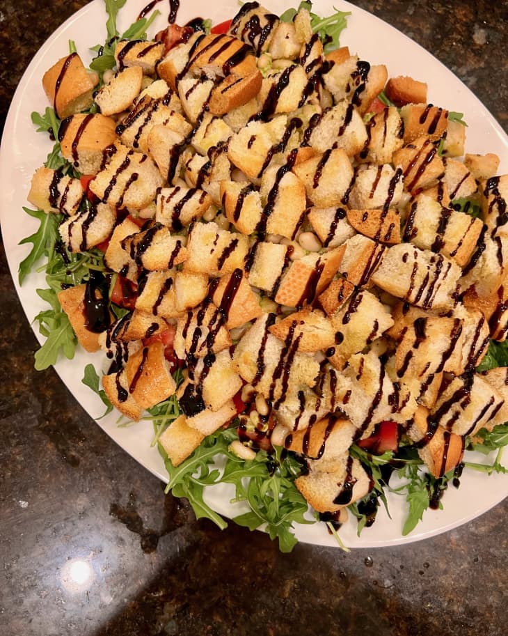 Salad with arugula, croutons, and balsamic glaze on a white plate.