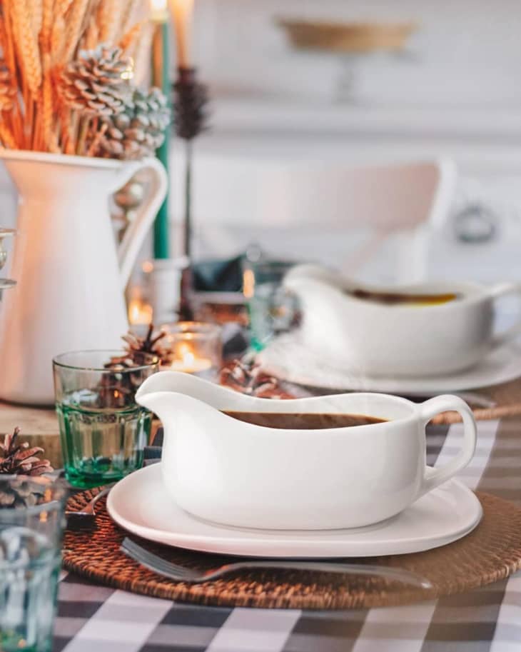 gravy boats on trays with buffalo check table cloth and warm lighting behind vase filled with wheat