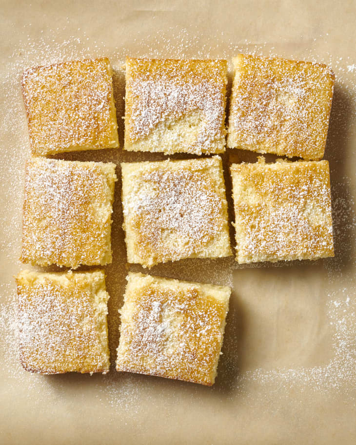 hot milk cake topped with powdered sugar on brown parchment paper