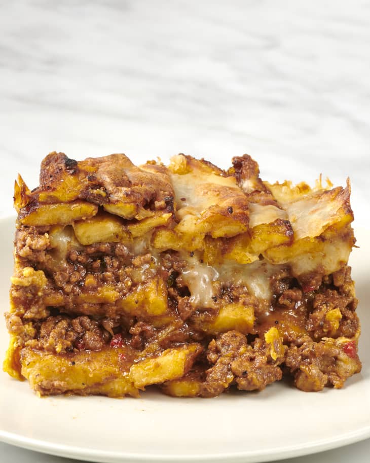 cross section of a slice of pastelon on a plate showing layers of plantain, cheese, and ground beef