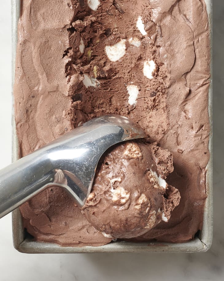 rocky road ice cream in a loaf pan with a scoop being taken