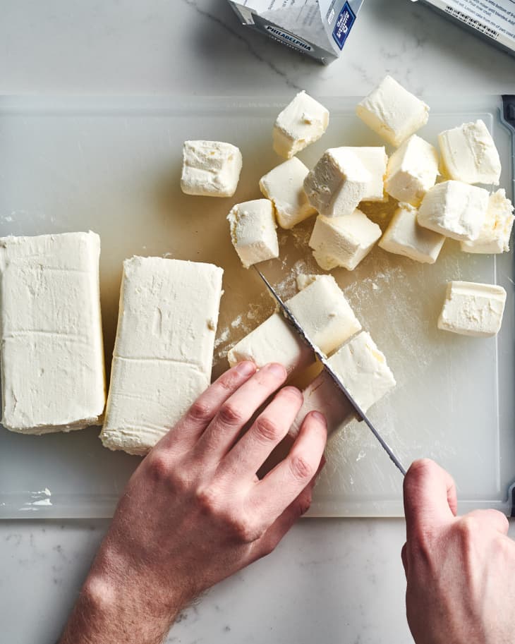 Cutting cream cheese on a cutting board.