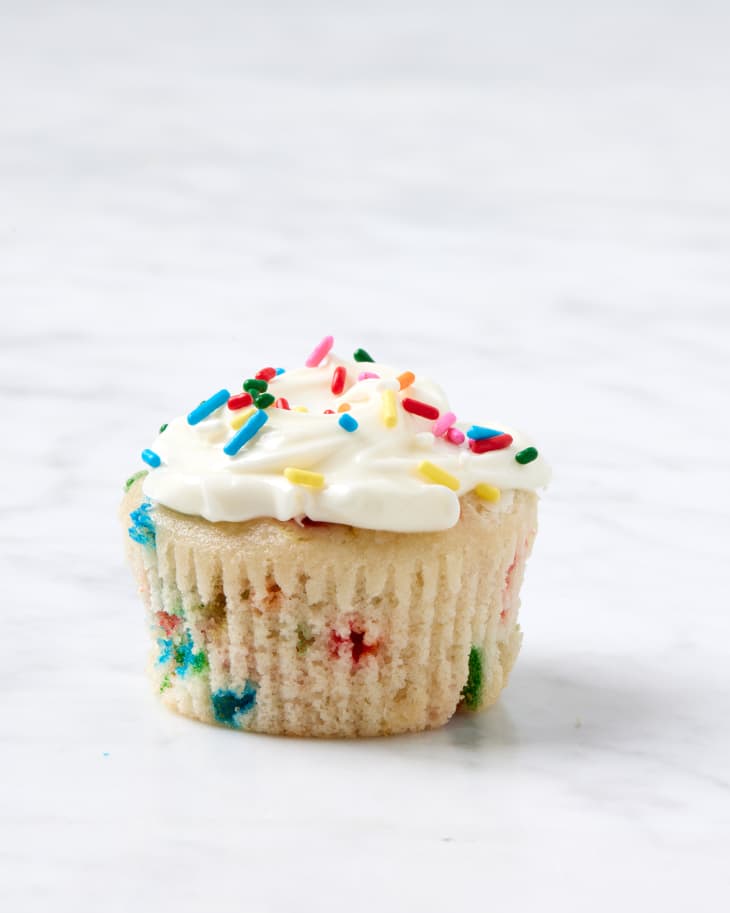 funfetti cupcake with frosting and sprinkles on top placed on a marble surface