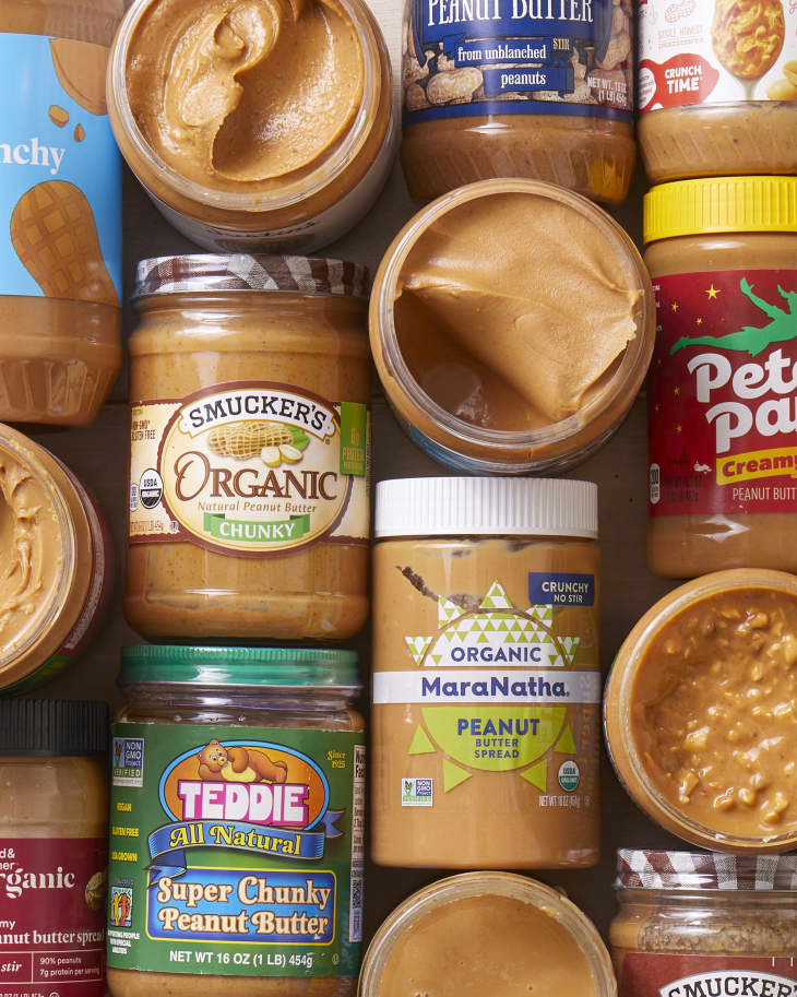 An opened jar of peanut butter with a small spoon Stock Photo