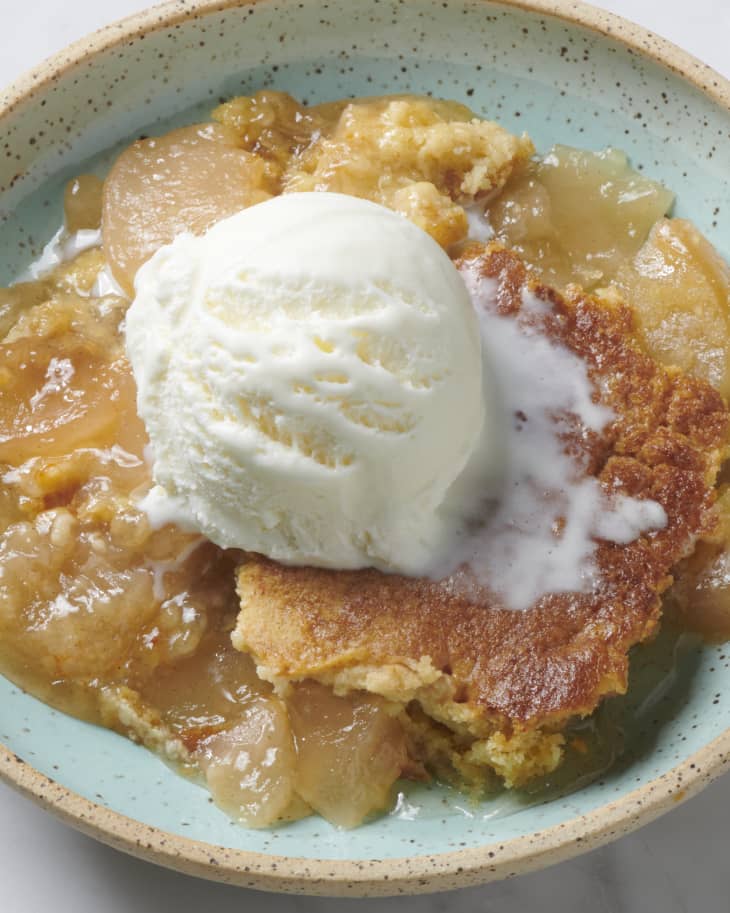 apple dump cake on a blue speckled plate with ice cream on top