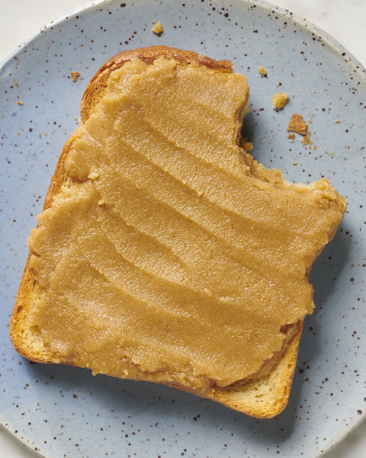 cashew butter spread on toast on a blue plate with a bite out